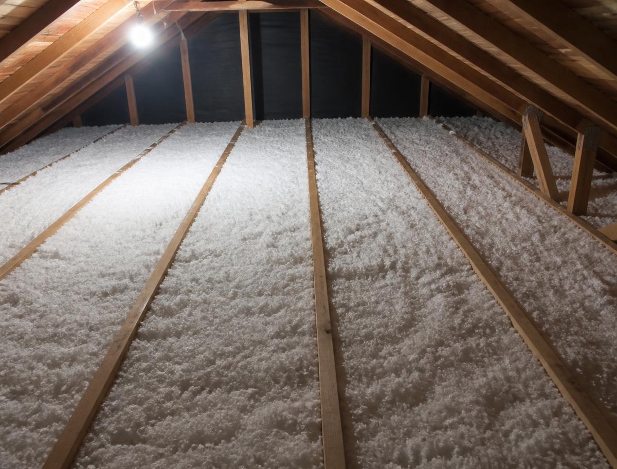 Attic floor covered with clean blown-in insulation between wooden joists
